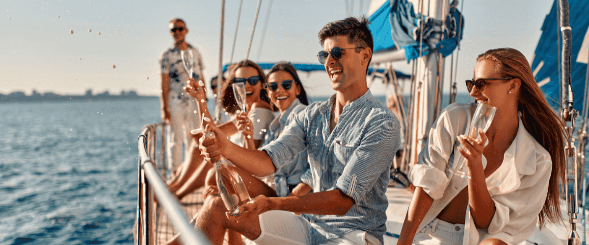 Group of friends on a boat on vacation popping a bottle of champagne