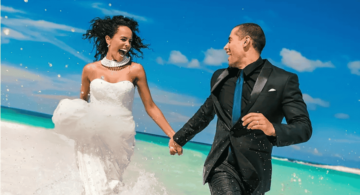 Bride and groom running through the ocean after their destination wedding