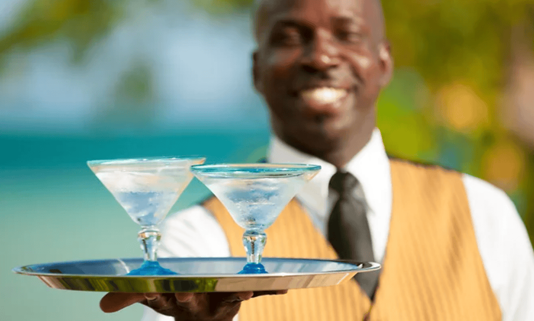 A butler at an all-inclusive resort holding two drinks on a tray