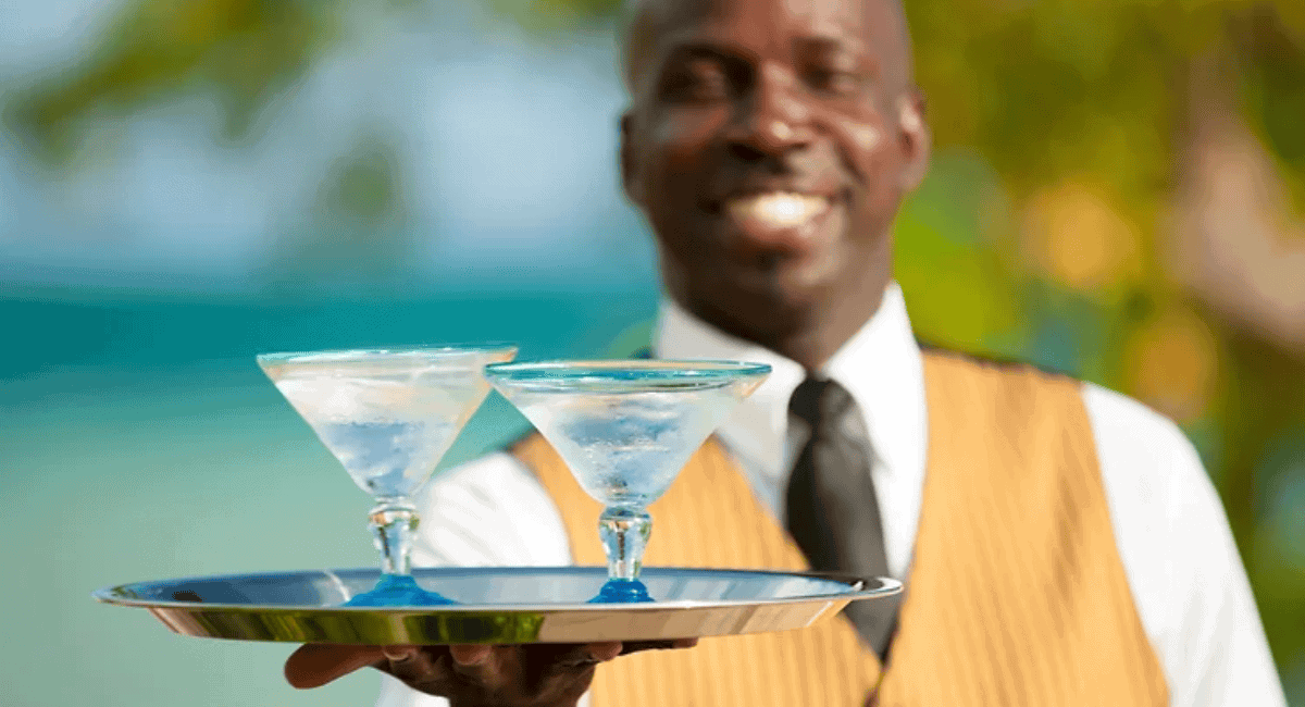 A butler at an all-inclusive resort holding two drinks on a tray