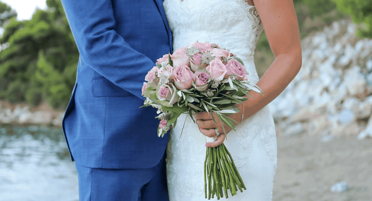 Close up of a man and woman's torsos on their wedding day with the bridal bouquet showcased