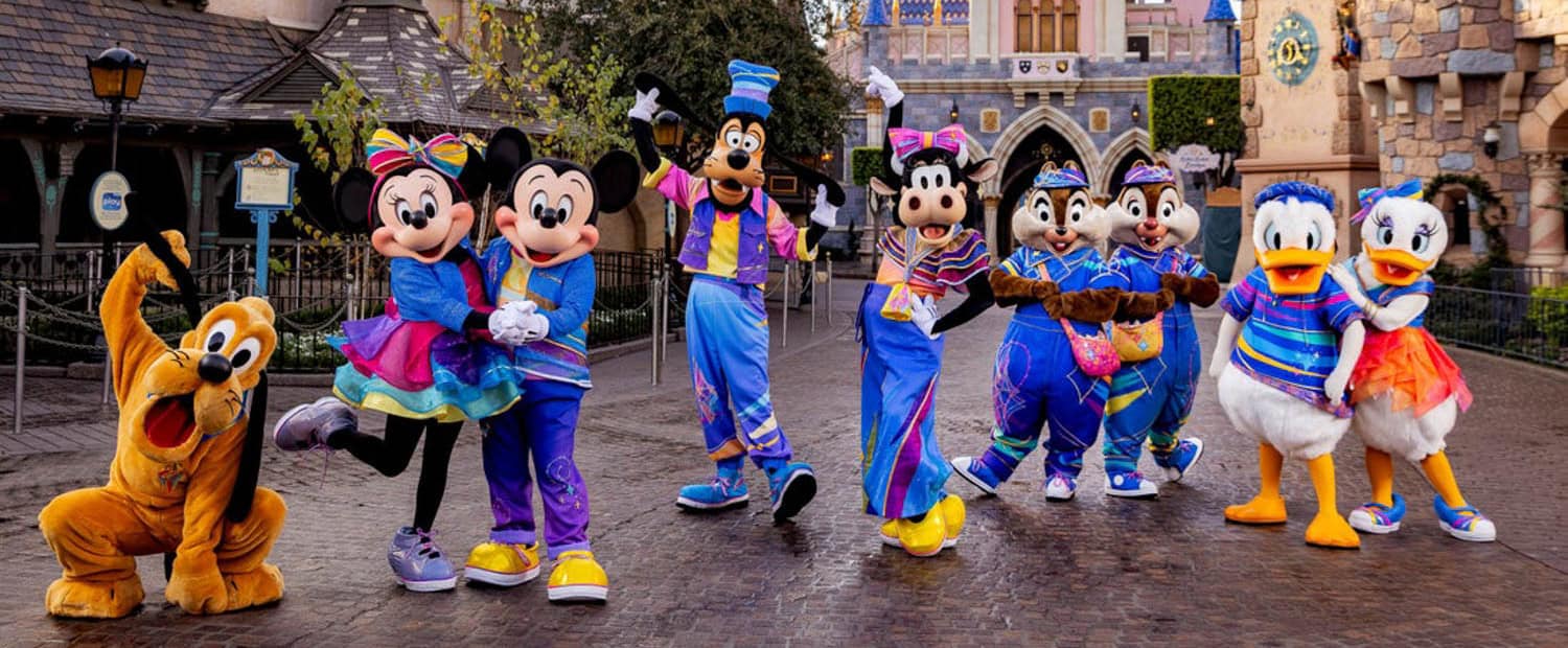 JT-Disney-11 Disney characters Pluto, Minnie Mouse, Mickey Mouse, Goofy, Clarabelle, Chip, Dale, Donald Duck, and Daisy Duck pose in colorful costumes at a theme park.
