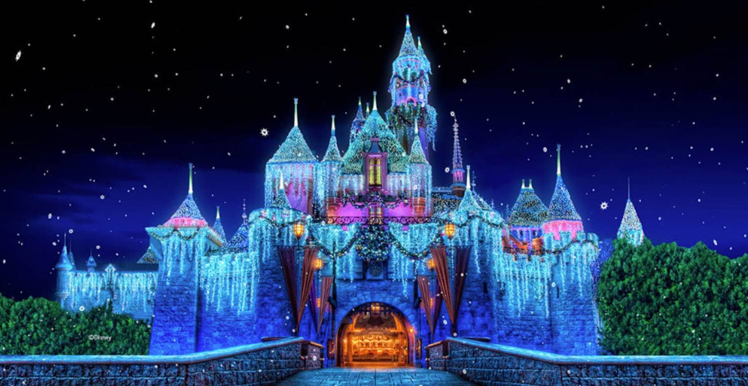 Screenshot Disneyland castle at night decorated with blue and white holiday lights, with snowflakes falling in the sky.