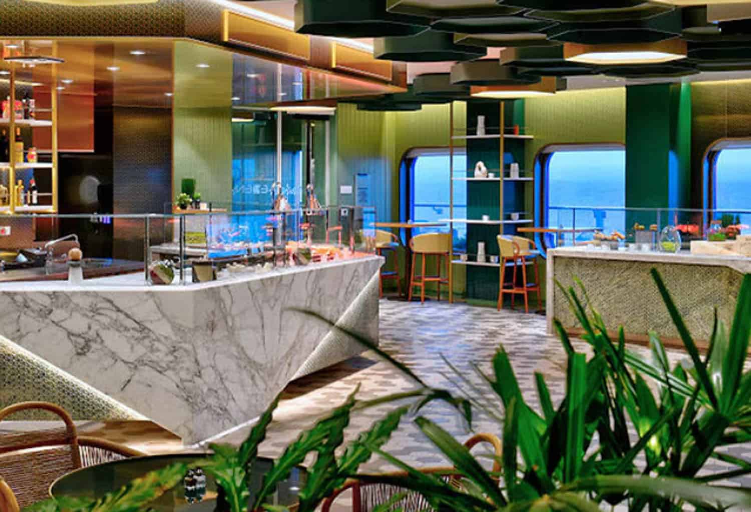 Modern cafe interior with marble counters, green accents, and large windows overlooking the ocean; plants and seating are visible in the foreground.
